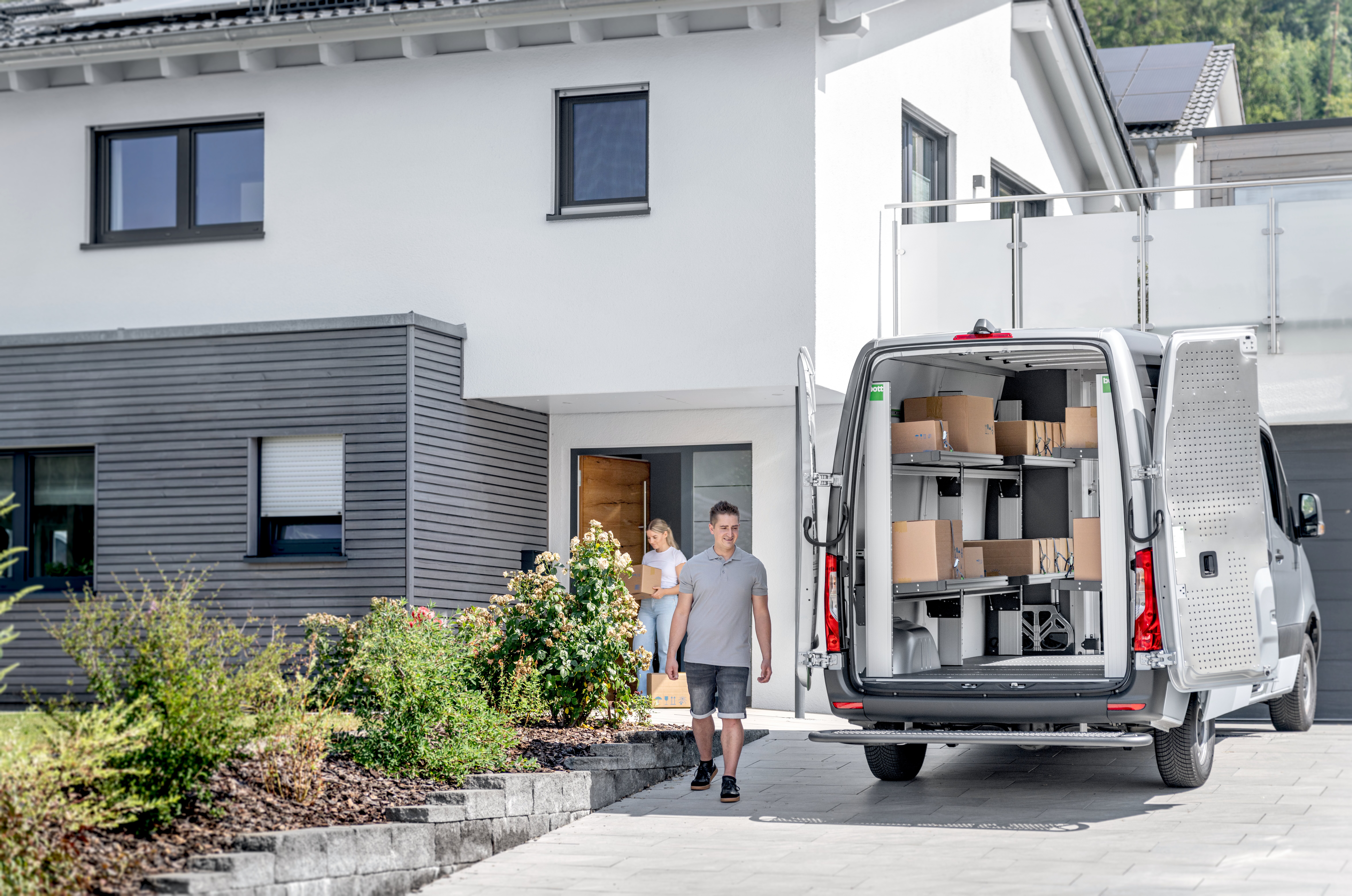 KEP-Zusteller liefert ein Paket aus einem Transporter mit bott vario3 Klappregalen an eine Empfängerin