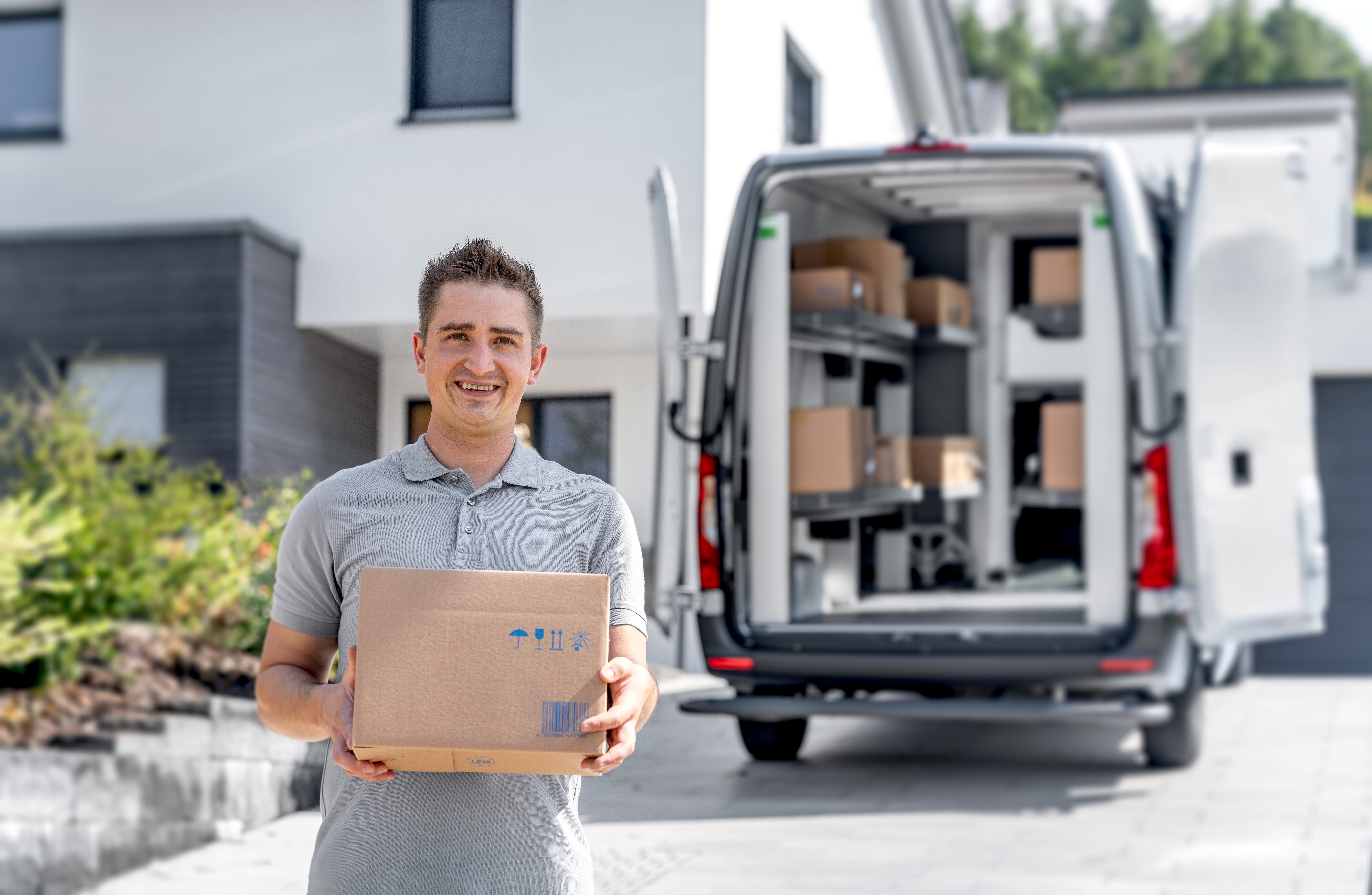 KEP-Zusteller hält ein Paket vor einem Lieferfahrzeug mit bott vario3 Klappregalen
